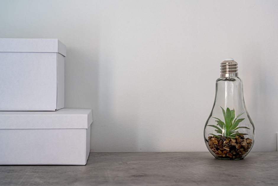 Clean minimalist desk scene with white boxes and lightbulb terrarium for modern decor.